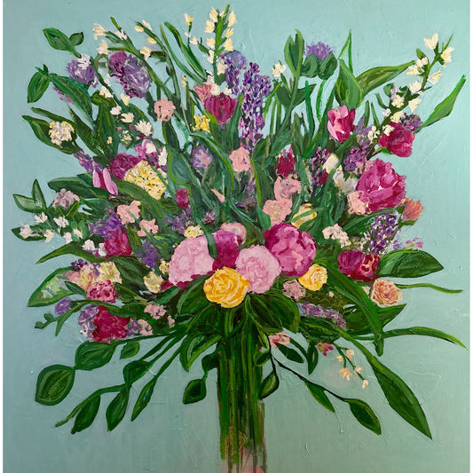Colorful bouquet of flowers in a clear vase against a light blue-green background